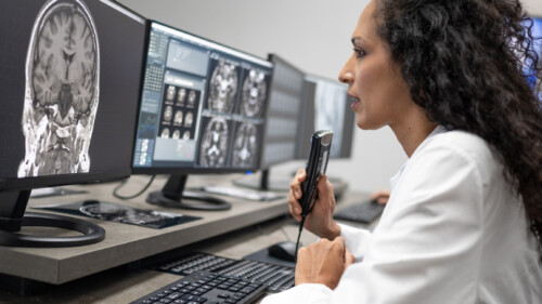 female radiologist speaking into a dictation recorder while looking at mri scan